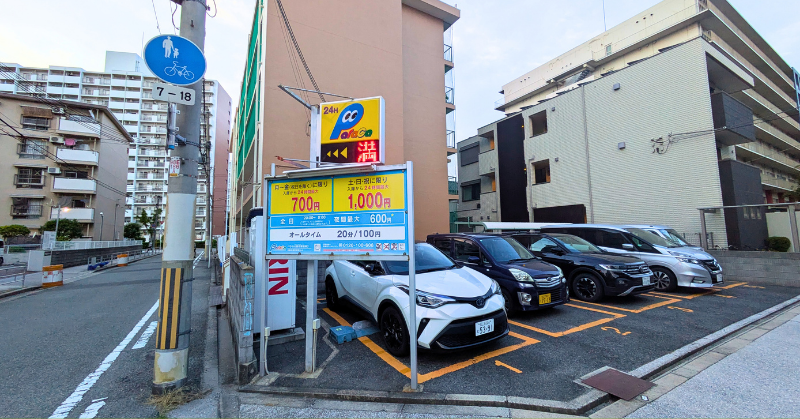 大阪万博周辺のコインパーキングに整然と並ぶ車両と、料金案内板が設置された住宅街の一角