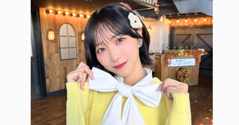 野口衣織の黄色のニットに白いリボンの服を着た写真