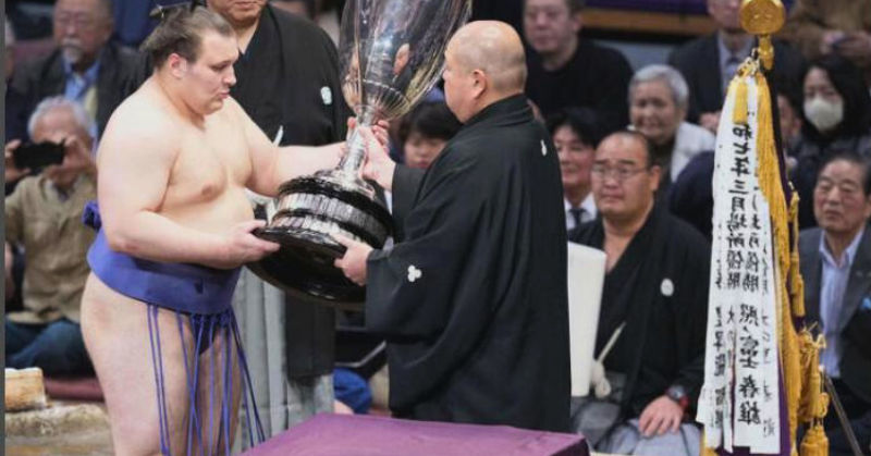 初優勝を飾った安青錦（左）は八角理事長から賜杯の贈呈を受ける