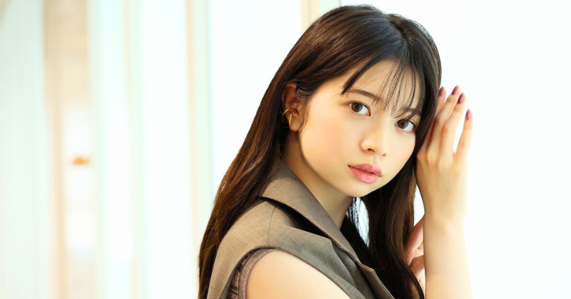 桜田ひよりが室内でこちらを見つめるポートレート写真。ナチュラルメイクで、片手を顔に添えるようなポーズを取っている。背景は白く明るい雰囲気で、柔らかい光に包まれている