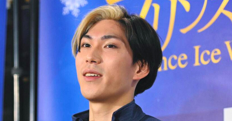 ブロンドと黒のツートンカラーの髪型をした田中刑事が、ブルーの背景の前でインタビューに応じている様子。背景には「Ice」や「Dance」などの英字が見える。