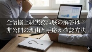 会議中のビジネスシーン。グラフを表示したノートPCと、疑問符のノートの上に『全信協上級実務試験の解答は？非公開の理由と手応え確認方法』の文字。